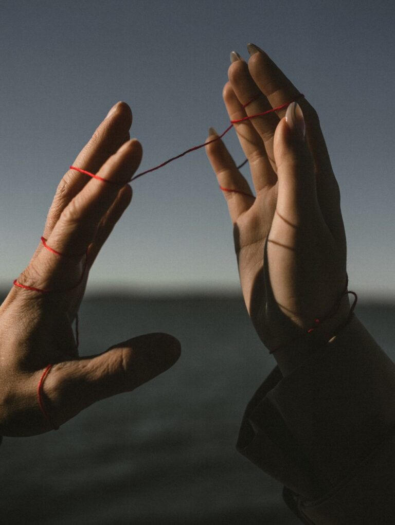 hands of couple connected with red string